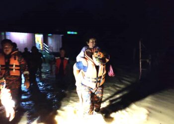 SEORANG anggota bomba dari Balai Bomba dan Penyelamat Kuala Pilah menggendong seorang warga emas sejauh 300 meter sambil meredah banjir di Kampung Kabong, Johol, Kuala Pilah. - UTUSAN/NOR AINNA HAMZAH