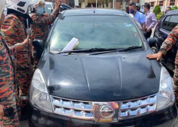 ANGGOTA bomba dan penyelamat berusaha membuka pintu kereta jenis Nissan Grand Livina untuk mengeluarkan seorang kanak-kanak perempuan yang terperangkap di parkir Pejabat Tanah dan Daerah Lipis di Lipis, Pahang. - FOTO/IHSAN BALAI BOMBA KUALA LIPIS