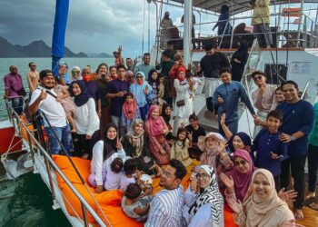SEBAHAGIAN daripada pengamal media dan keluarga yang menyertai sambutan Hari Raya Aidilfitri di atas bot persiaran Seasation di Langkawi, semalam. - UTUSAN/NUR AMALINA AZMAN