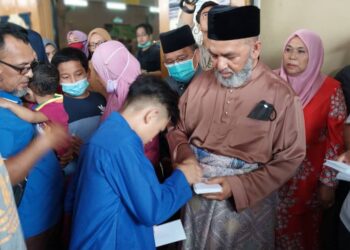 SYED Abu Hussin Hafiz Syed Abdul Fasal memberi duit raya kepada kanak-kanak pada majlis sambutan Aidilfitri di Dewan Sungai Kerang di Bukit Gantang hari ini. - UTUSAN/WAT KAMAL ABAS