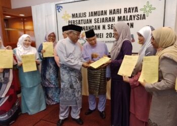 HASAN Malek (tengah) melihat borang keahlian seumur hidup yang diserahkan kepadanya pada Jamuan Hari Raya Persatuan Sejarah Malaysia Cawangan Negeri Sembilan di Seremban. - UTUSAN/NAZARUDIN SHAHARI