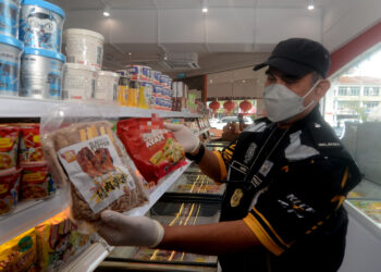 MOHD. Wazir Khalid menunjukkan perbezaan antara produk makanan halal serta tidak halal yang diletakkan bersama dalam sebuah peti sejuk dalam serbuan di sebuah kedai serbaneka di Jalan Raja Uda, Butterworth, Pulau Pinang hari ini. - UTUSAN/IQBAL HAMDAN