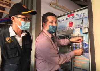 DR. Mohd. Ridzuan Mohd. Lutpi menampal pelekat sita pada salah satu mesin air automatik yang beroperasi tanpa lesen serta kotor dalam operasi di sekitar Muar, di sini. UTUSAN/NUR ALINA HASSAN