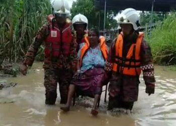 ANGGOTA  bomba membantu memindahkan seorang warga emas dalam kejadian banjir kilat di Gurun, hari ini.
