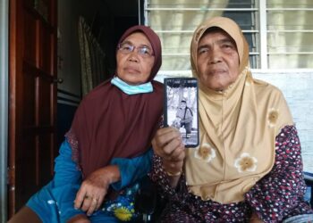 RUBIAH Basok (kanan) dan adiknya, Haniah, 61, menunjukkan gambar Allahyarham Zunairi yang terkorban dalam kemalangan di Bukit Rotan, Kuala Selangor, Selangor.