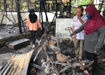 FARIDAH Lanar (kanan) bersama suami dan anak perempuannya melihat motosikal mereka  yang hangus dalam kebakaran di Kampung Kerinting, Gua Musang, Kelantan. -UTUSAN/ AIMUNI TUAN LAH