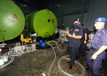 KAMARUL Zaman Mamat (dua dari kanan) melihat peralatan yang digunakan dalam  penyeludupan minyak diesel dalan Op Bersepadu Kontraban di kawasan Perindustrian Desa Plentong Masai, Johor Bahru. - UTUSAN/RAJA JAAFAR ALI