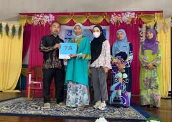 NUR Fara Niza Zainal (dua dari kiri) menerima sijil peperiksaan SPM 2021 dari Pengetua SMK Batu Kikir (Model Khas) Md Nazri Hassan Kuala Pilah hari ini.