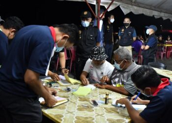 ANGGOTA penguat kuasa JKNT mengeluarkan notis kompaun kepada pelanggan di sebuah restoran pada Op Gomo Asap Malam di Kuala Terengganu, malam semalam. - UTUSAN/PUQTRA HAIRRY ROSLI
