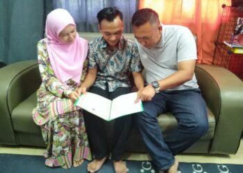 MOHD. JUSNI Yusof (kanan) dan Azizah Abu Hanifah sedang melihat keputusan peperiksaan Sijil Pelajaran Malaysia (SPM) anak mereka, Afif Jazimin di kuarters guru Felda Kota Gelanggi Dua di Jerantut, Pahang. - UTUSAN/HARIS FADILAH AHMAD