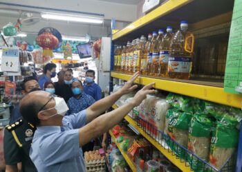 NGWE Hee Sem meninjau minyak masak botol di sebuah premis sewaktu membuat pemeriksaan di Pasar Awam Jasin, Melaka. - UTUSAN/AMRAN MULUP