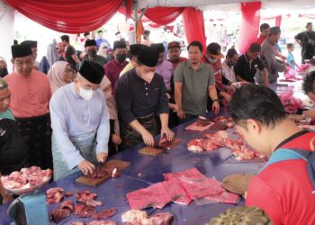 MOHD. ALI Mohd. Rustam (tiga dari kiri) melapah daging korban sebelum diagihkan kepada orang ramai pada program korban berkelompok di luar pekarangan Masjid Al-Azim, Bukit Palah, Melaka. - UTUSAN/RASUL AZLI SAMAD