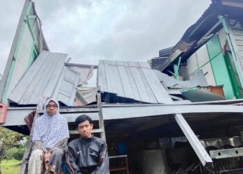 ROSNAH Daud (kiri) bersama cucunya hanya mampu termenung di tangga rumah selepas sebahagian besar rumah pusaka berusia 100 tahun itu musnah dibadai ribut di Kampung Lubuk Besar, Santan, Padang Besar Perlis hari ini. - UTUSAN/SYED AZLAN SAYID HIZAR