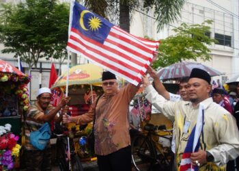 ROSNAZLI Amin (tengah) memegang bendera Malaysia bersama pengayuh beca Program Semarak Gemilang 2022 Negeri Kelantan di Masjid Al-Baro’ah Pasar Besar Siti Khadijah, Kota Bharu, Kelantan hari ini. - UTUSAN/ROSLIZA MOHAMED