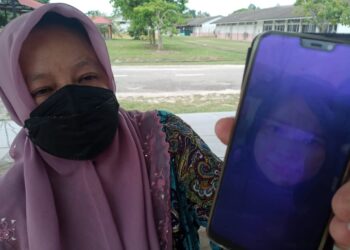 NORAINI Tabilin menunjukkan gambar Yusni Hamid yang maut dalam kemalangan di simpang empat Kampung Dalam Kemunting, Pasir Puteh, Kelantan hari ini. - UTUSAN/TOREK SULONG