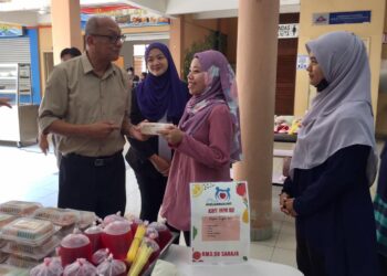 DR. Mazlan Abd. Ghaffar (kiri) membantu mengagihkan Menu Keluarga UMT kepada pelajar di pusat pengajian itu di Kuala Nerus, Terengganu, hari ini. - UTUSAN/TENGKU DANISH BAHRI TENGKU YUSOFF