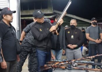 KHAIRUL Dzaimee Daud (tiga dari kiri) melihat lima laras senapang angin yang dirampas dalam operasi penguatkuasaan Jabatan Imigresen di Kuala Gula, Bagan Serai  semalam. -  UTUSAN/WAT KAMAL ABAS