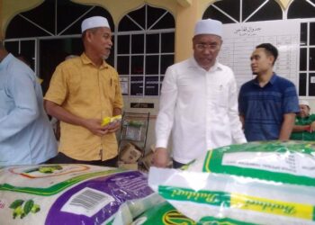 IDRIS Ahmad (dua dari kanan) melihat barangan yang dijual dalam program Jualan Bergerak Bantu Rakyat di Kampung Sungai Petai, Bukit Gantang hari ini. - UTUSAN/WAT KAMAL ABAS