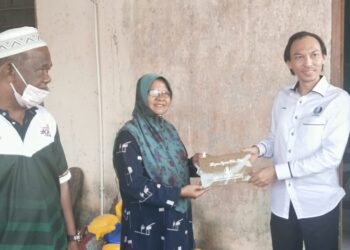 DR. Ahmad Azrin Adnan (kanan) menyampaikan sumbangan kepada  salah seorang mangsa ribut di Kampung Bukit Kolam, Ajil di sini, hari ini.