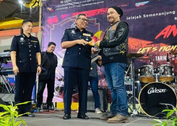 RUSLAN KHALID menyampaikan cenderahati kepada Awie pada program Kempen Anti Scam-PDRM 2022 (Awie Ride), di Seremban malam tadi.-UTUSAN/AFIFI HAFIZ MOHD. NOR.
