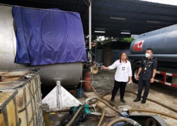 NORENA Jaafar (kiri) menunjukkan tangki simpanan diesel yang disita dalam serbuan di sebuah premis di Kawasan Perindustrian Krubong, Melaka.