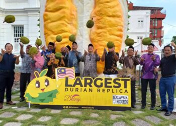 SANTHARA Kumar (enam dari kanan) melambung buah durian sebagai gimik replika durian terbesar mendapat pengiktirafan MBOR di Bandar Hilir, Melaka. - UTUSAN/AMRAN MULUP