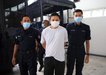 TERTUDUH (tengah) diiring oleh dua anggota polis semasa dibawa ke Mahkamah Tinggi Kota Bharu, Kelantan hari ini.-UTUSAN/ KAMARUL BISMI KAMARUZAMAN