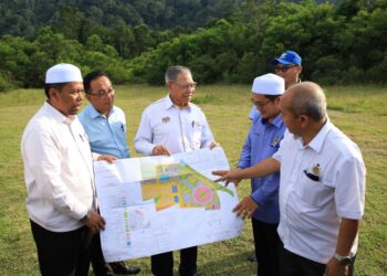 MUSTAPA Mohamed (tengah) menunjukkan pelan struktur pembangunan Kompleks Sukan Bukit Merbau di Selising, Pasir Puteh, Kelantan hari ini/FOTO : KAMARUL BISMI KAMARUZAMAN
