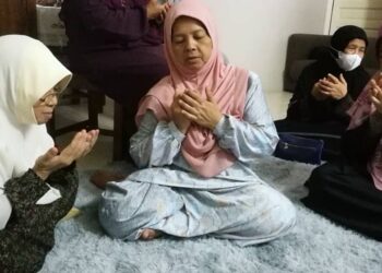 ZUBAIDAH Abdul Ghani (tengah) membaca doa buat arwah suaminya, Zahari Zakaria di rumahnya di Taman Desa Solehah, Mak Chili, Kemaman, hari ini. - UTUSAN/NIK NUR IZZATUL HAZWANI NIK ADNAN