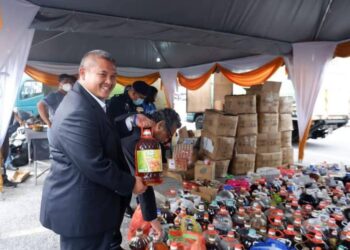 RAIS Yasin menunjukkan minyak masak terpakai yang dikumpul dalam program Singgit Seposen di Dewan Alamanda, Jasin, Melaka. - UTUSAN/AMRAN MULUP