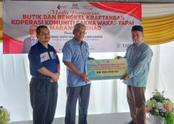 ZAZALI Haron (tengah) menyampaikan replika cek kepada Pengerusi Kowata, Zakaria Salleh (kanan)  pada majlis perasmian butik dan bengkel kraftangan Kowata di Marang, semalam. - UTUSAN/KAMALIZA KAMARUDDIN