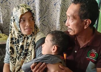 HAFIZ AL ARSHAD menunjukkan badan anaknya Muhammad Alif dan diperhatikan oleh isterinya, Lina Rais (kiri) di Kampung Seri Màkmor Plentong, Johor Bahru.