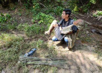 MOHD. FITRI ABDUL RAZAK mendukung Painah untuk dibawa ke tanah lapang selepas ditemukan berhampiran lopak air dalam kebun kelapa sawit di Kampung, Parit Kasih Sayang Senggarang.