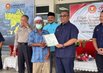 MURAD Ahmad menerima geran tanah daripada Muhammad Sanusi Md. Nor pada Majlis Penyerahan Geran kepada Peserta Felcra Kampung Kok, di Pejabat Daerah dan Tanah Langkawi, hari ini. -UTUSAN/NUR AMALINA AZMAN