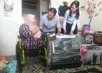 NGA Kor Ming (tengah) menyampaikan sumbangan peralatan membuat kuih kepada Zaitun Ibrahim di Ipoh hari ini. - UTUSAN/SAYED HESHAM IDRIS