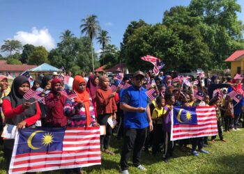 PENDUDUK Orang Asli suku Mendriq dan Batek mengibar Jalur Gemilang sempena sambutan Hari Kebangsaan pada Program Komuniti Sejahtera Kemas di Kampung Pasir Linggi, Pos Lebir, Gua Musang, Kelantan. - UTUSAN/AIMUNI TUAN LAH