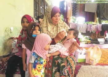 SUHADA Hamzah bersama anaknya, Siti Fatimah Mohd. Rosdi yang menghidap sumbing lelangit serta Siti Aufa (kiri) menderita masalah buah pinggang disebabkan Sindrom Nefrotik ketika ditemui di rumahnya 
di Kampung Stong Dabong, Kuala Krai, Kelantan. –  mingguan/ROSMIZAN RESDI