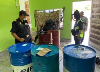 POLIS dan penguat kuasa KPDNHEP memeriksa tong dram dipercayai berisi diesel dan petrol bersubsidi di sebuah rumah di Kampung Kolam, Padang Besar, Perlis semalam. - UTUSAN