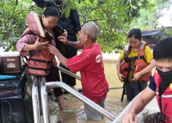 ANGGOTA APM membantu warga emas meninggalkan kediaman mereka yang dinaiki air di Kampung Laut Batu 10, Skudai.