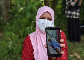 NORMAWATI Jaafar menunjukkan gambar abangnya, Norzi yang ditemukan mati dalam keadaan berlumuran darah di Kampung Merua, Parit hari ini. - UTUSAN/ MOHAMAD HAFIZI MOHD. SAID