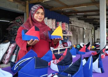 NORWILIA Mohd. Zawawi menunjukkan sebahagian daripada tanjak Jalur Gemilang yang dijual sempena sambutan Bulan Kebangsaan Ke-65 di Bukit Tunggal, Kuala Nerus, hari ini. - UTUSAN/KAMALIZA KAMARUDDIN
