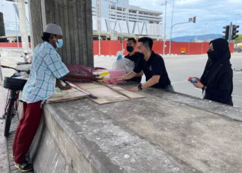 LEE BOON KAE (tengah) menyerahkan sumbangan makanan kepada golongan  gelandangan di Jalan Bagan Dalam, Butterworth, Pulau Pinang hari ini.