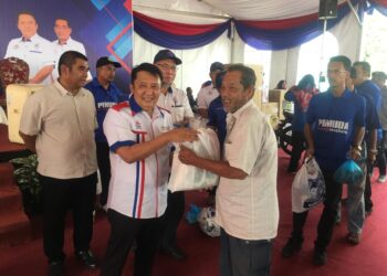 AHMAD Jazlan Yaakub (kanan) menyampaikan bantuan bakul makanan kepada penerima pada Program Jelajah Mini Karnival  Keluarga Malaysia Felcra Berhad 2022 di Kampung Padang Limau, Bukit Bakar, Machang, Kelantan hari ini.-UTUSAN/ROSMIZAN RESDI