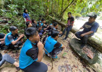 NIK Mud Nik Him (kanan) menyampaikan arahan kepada pelajar PPKI yang menyertai aktiviti meredah hutan di Pasir Puteh, Kelantan, hari ini.-UTUSAN/TOREK SULONG