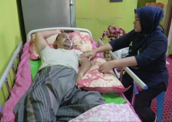 ROZILAWATI Ismail (kanan) menjaga Mohd. Hairol Yusof yang terlantar lumpuh akibat diserang angin ahmar, bulan lalu di kediaman mereka di Kuantan, Pahang. - UTUSAN/ DIANA SURYA ABD WAHAB