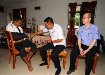 MOHD. HAIRI MAD SHAH menyampaikan faedah Perkeso kepada Izwan Othman (kiri) yang mengalami kecederaan mengakibatkan pergelangan tangannya dipotong sambil diperhatikan oleh Pengarah Perkeso Johor. Tong Sing Chuang di rumahnya di Taman Saujana, Plentong, Johor Bahru.