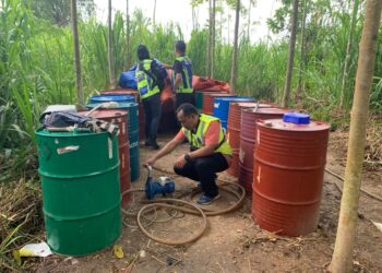 ANGGOTA polis Padang Besar memeriksa tong drum berisi petrol dan diesel yang ditemukan di sebuah stor haram di Kampung Kok Mak, Padang Besar, Perlis semalam. - UTUSAN
