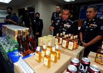KAMARUL Zaman Mamat menunjukkan arak tiruan dan tidak bercukai yang dirampas dari sebuah kedai di Taman Gembira, Johor Bahru. - UTUSAN/RAJA JAAFAR ALI