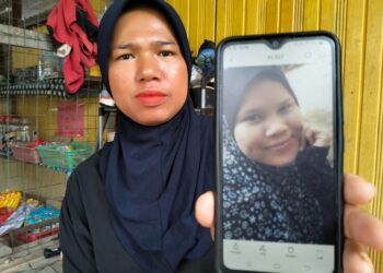 HAFISAH Ismail menunjukkan gambar adiknya, Siti Zaleha yang hilang selepas keluar dari rumahnya di Kampung Naga Ibu, Tumpat, Kelantan. - UTUSAN/ROHANA ISMAIL
