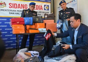 SAHARUDDIN Mohd. Kia (kanan) menunjukkan sebahagian daripada barang tiruan pelbagai jenama popular yang dirampas di Kuala Terengganu. - UTUSAN/PUQTRA HAIRRY ROSLI